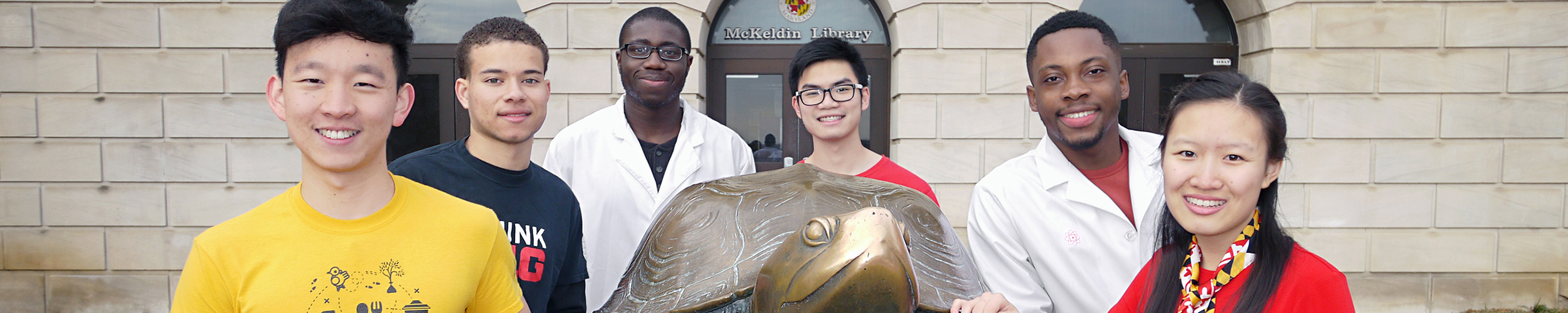 A group of HPAO students outside the library, posing with a bronze statue of Testudo.